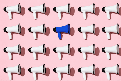 Wall of white megaphones with one blue megaphone in the center